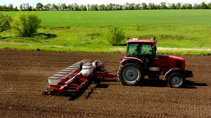 aerial view tractor cuts furrows in farm field for sowing farm tractor with rotary harrow plow preparing land for sowing. Tractor with harrows prepares the agricultural land for planting crop - Powered by Adobe