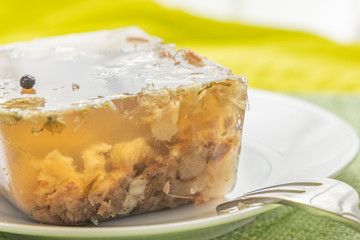 Jellied beef on a plate with fork. A piece of jelly from meat. Closeup.