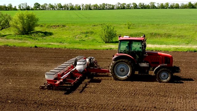 aerial view tractor cuts furrows in farm field for sowing farm tractor with rotary harrow plow preparing land for sowing. Tractor with harrows prepares the agricultural land for planting crop