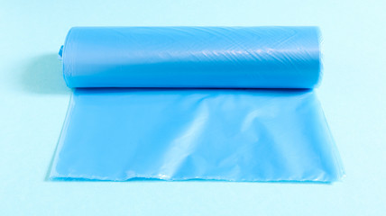 One roll of plastic garbage bags in blue on a blue background. Bags that are designed to accommodate garbage in them and used at home and placed in various garbage containers.