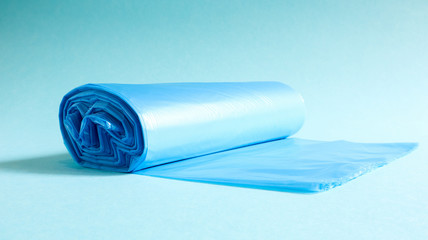 One roll of plastic garbage bags in blue on a blue background. Bags that are designed to accommodate garbage in them and used at home and placed in various garbage containers.