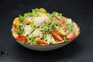 Caesar salad with shrimp in a bowl on a black background.