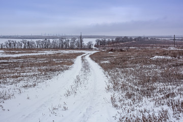 rural road in winter, bumpy, snow-covered local countryside road, winter landscape with panorama of the road