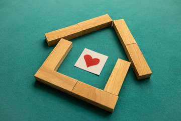 House made of wooden blocks with a red heart inside on a blue background. Low angle view, close-up.
