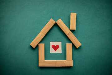House made of wooden blocks with a red heart inside on a blue background. Flat lay, top view, copy space.