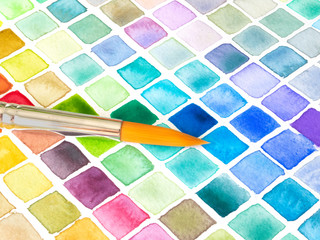 Colorful squares of a watercolor color pallet and a brush