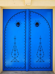 Tunisian blue metal traditional door with a black pattern and doorknobs