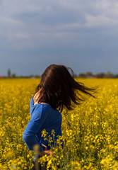 Naklejka na ściany i meble Young woman in rape field swinging with hair