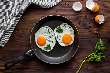 Fried eggs on frying pan on wooden table top-down