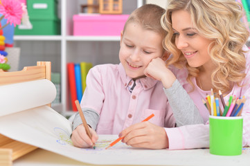 Portrait of smiling mother and son drawing with pencils