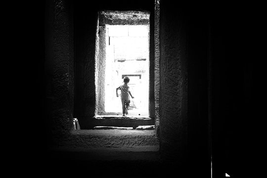 Rear View Of Boy Walking Through Doorway