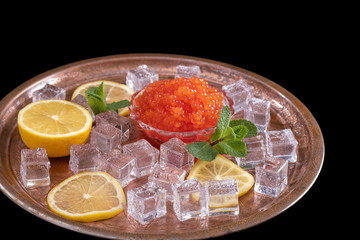 Red salmon caviar on plate with fresh lemon, ice cube, mint. Healthy diet. Selective focus Copy space Space for text