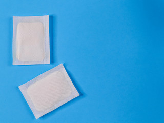 Two adhesive plasters on the left on a blue background. Close up, top view and place for text.