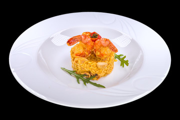 Tasty risotto with shrimp in a white plate, isolated on black background