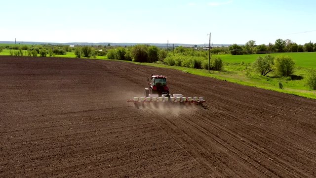 aerial view tractor cuts furrows in farm field for sowing farm tractor with rotary harrow plow preparing land for sowing. Tractor with harrows prepares the agricultural land for planting crop