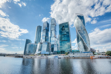 Skyscrapers of Moscow city on the river bank with reflection of clouds on the glass of buildings
