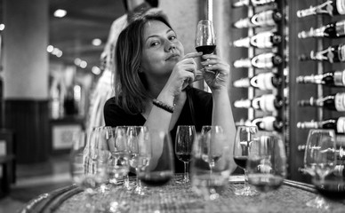 young woman drinking wine in bar, glasses of champagne, portwein and red wine on the 
 wooden table, black and white, wine tasting concept