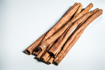 group of dry cinnamon sticks served on white table surface