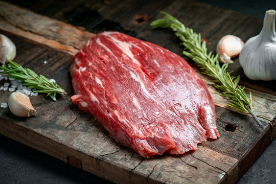 Raw flank beef steak and ingredients for cooking on a wooden Board, close up