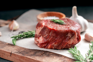 Prepared for grilling Raw steak filet Mignon beef on a wooden table with herbs