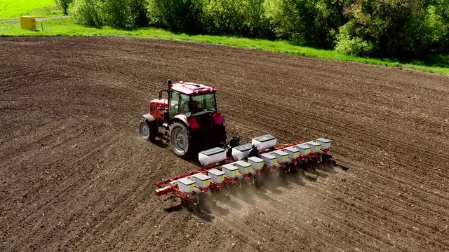 aerial view tractor cuts furrows in farm field for sowing farm tractor with rotary harrow plow preparing land for sowing. Tractor with harrows prepares the agricultural land for planting crop