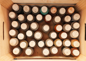 Paint on wood in old and dirty bottles in a wooden box. Top view and close-up.