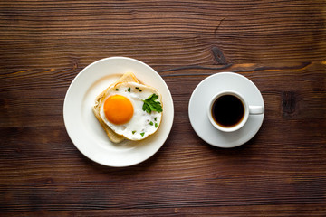 Fried eggs sandwich on plate - dark wooden dinner table top view
