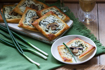 Puffs with cheese, spinach and mushrooms, served with wine and green onions. Rustic style.