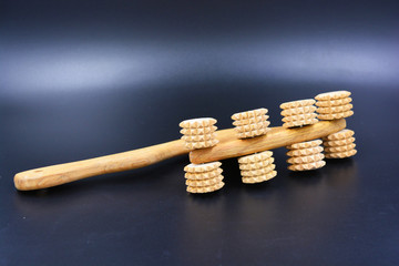 Wooden massager for back and body made of wood located on a black background.