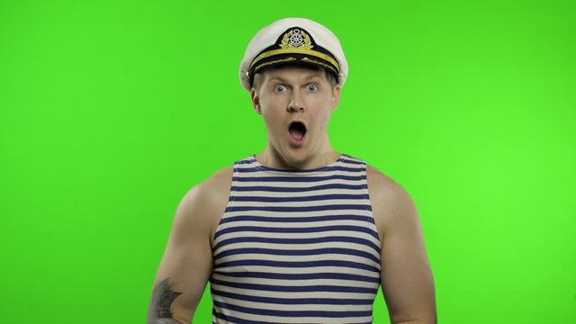 Young sailor man expresses shock, looks surprised. Seaman guy in sailor's vest