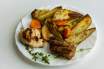 Top down view of a dish consisting of grilled meat slices and fried potatoes on white plate