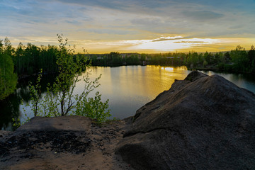 View from the top of a rocky cliff on a small lake and picturesque bright sunset