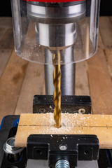 Drilling in wood with professional tools. Work on a bench drill.