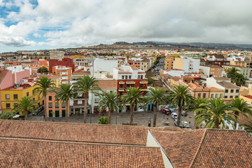 Obraz premium The top of highest church tower. Aerial view of the historic town of San Cristobal de La Laguna in Tenerife showing streets and tiled roofs of historic buildings with horizon in the background