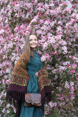 Russian fashionable girl in vintage Pavlovo Posad shawl. Pink flowers of blossoming apple-tree,...