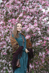 Russian fashionable girl in vintage Pavlovo Posad shawl. Pink flowers of blossoming apple-tree,...