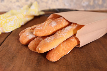 French baguettes in paper bags on wooden background.