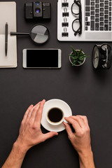 Coffee break flat lay concept with male hands holding white espresso cup on abstract desk background