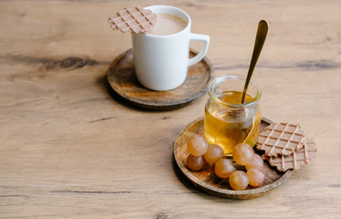 Healthy snack set with muscat grapes, honey and coffee with waffles on wooden background. 