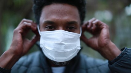 African black man putting on outbreak mask prevention, young man wearing covid mask
