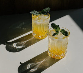 Refreshing iced yellow cocktails under sun with dark shades on white background. 