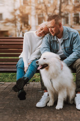 Couple having rest on bench, taking care of their dog