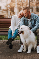 Couple having rest on bench, taking care of their dog