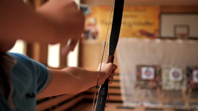 The archer shoots a bow and misses. Preparing for shooting indoor archery. The archer inserts an arrow into the bow to fire and raises the weapon to fire. Archery shot at target.