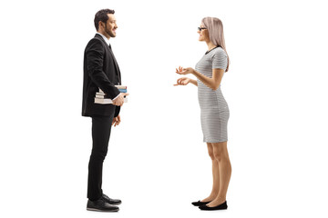 Man in a black suit holding books and talking with a blond young woman