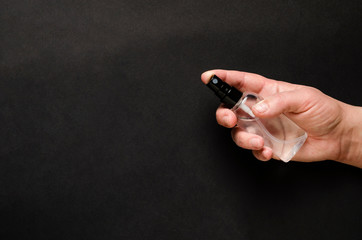 Hand sanitizer bottle in hand closeup.Black background. Antibacterial liquid against 19-ncov.Call for hand disinfection. Stop coronavirus concept. Using antibacterial gel for hands during quarantine.