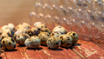 Quail eggs on red wooden surface on blurred background