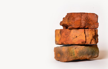 Stack of several old broken red bricks on a light gray background. Building. Minimal industrial background.