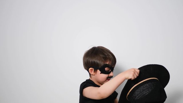 boy superhero in a black mask is trying to catch a hat flying in him
