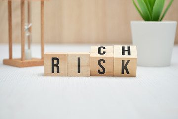 Abstract words risk and rich on wooden cubes.